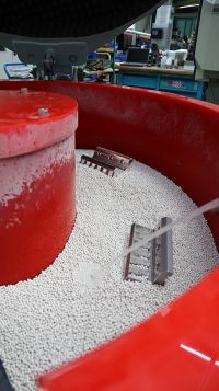 Mittels Vibrationen wird Granulat in Schwingungen versetzt. Die Bauteile rotieren mit und werden den Anforderungen entsprechend bearbeitet